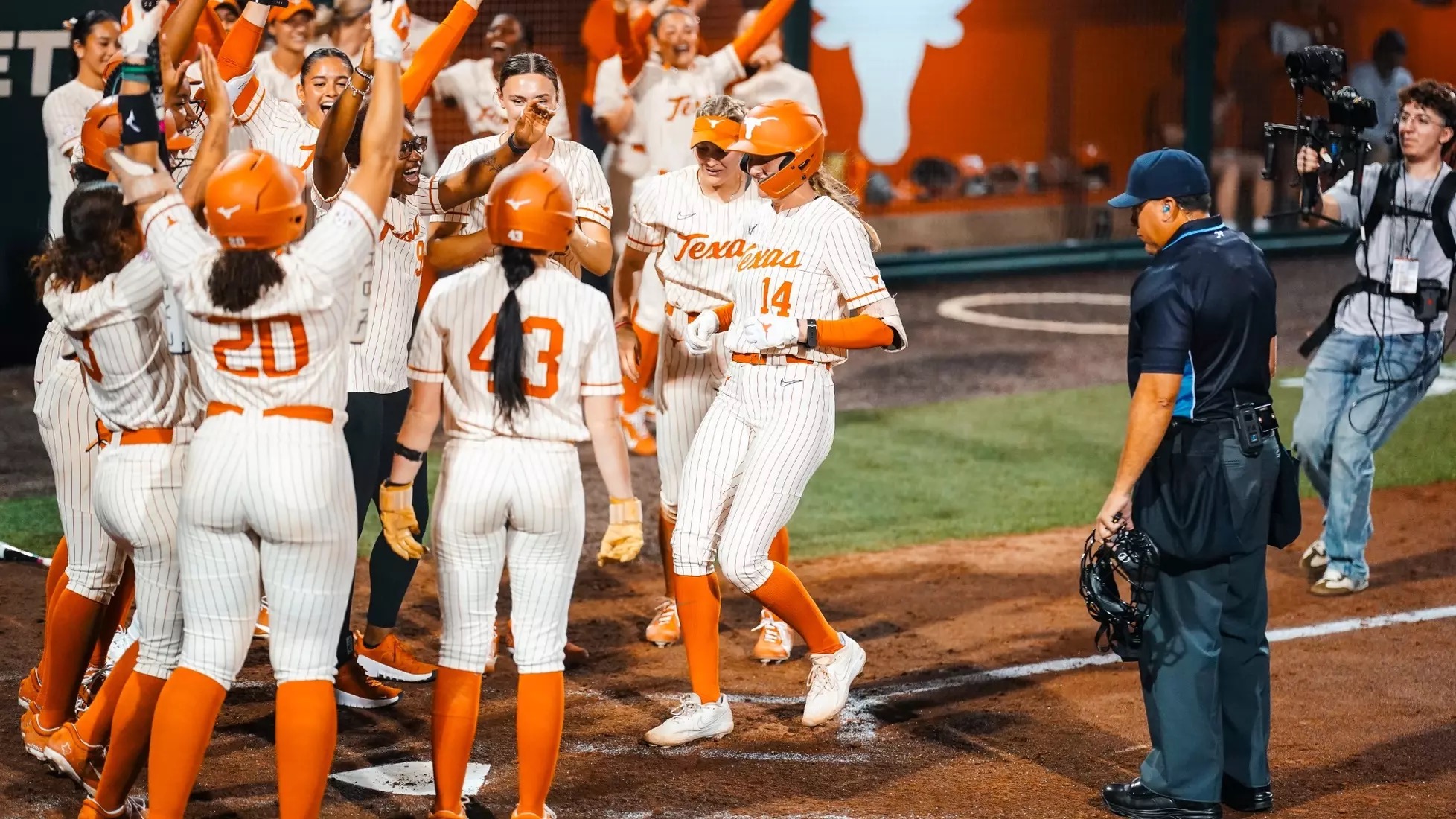 Reese Atwood and Texas teammates including Leighann Goode celebrate at home plate after a Longhorns home run