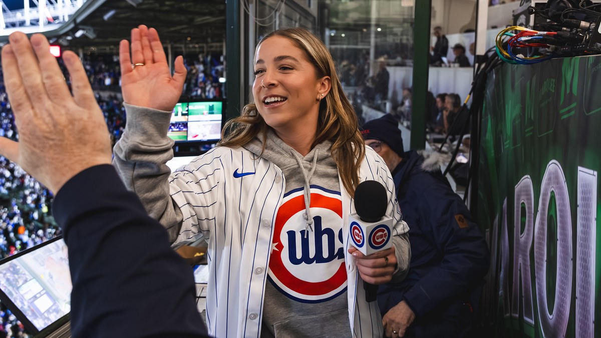 Bella Dayton in a Cubs jersey high-fives in the Wrigley Field broadcast booth