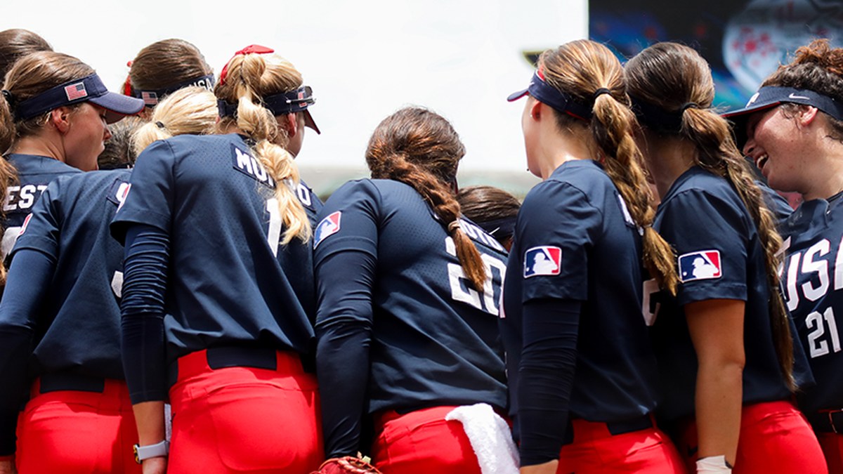 USA Softball players huddle with their backs to the camera